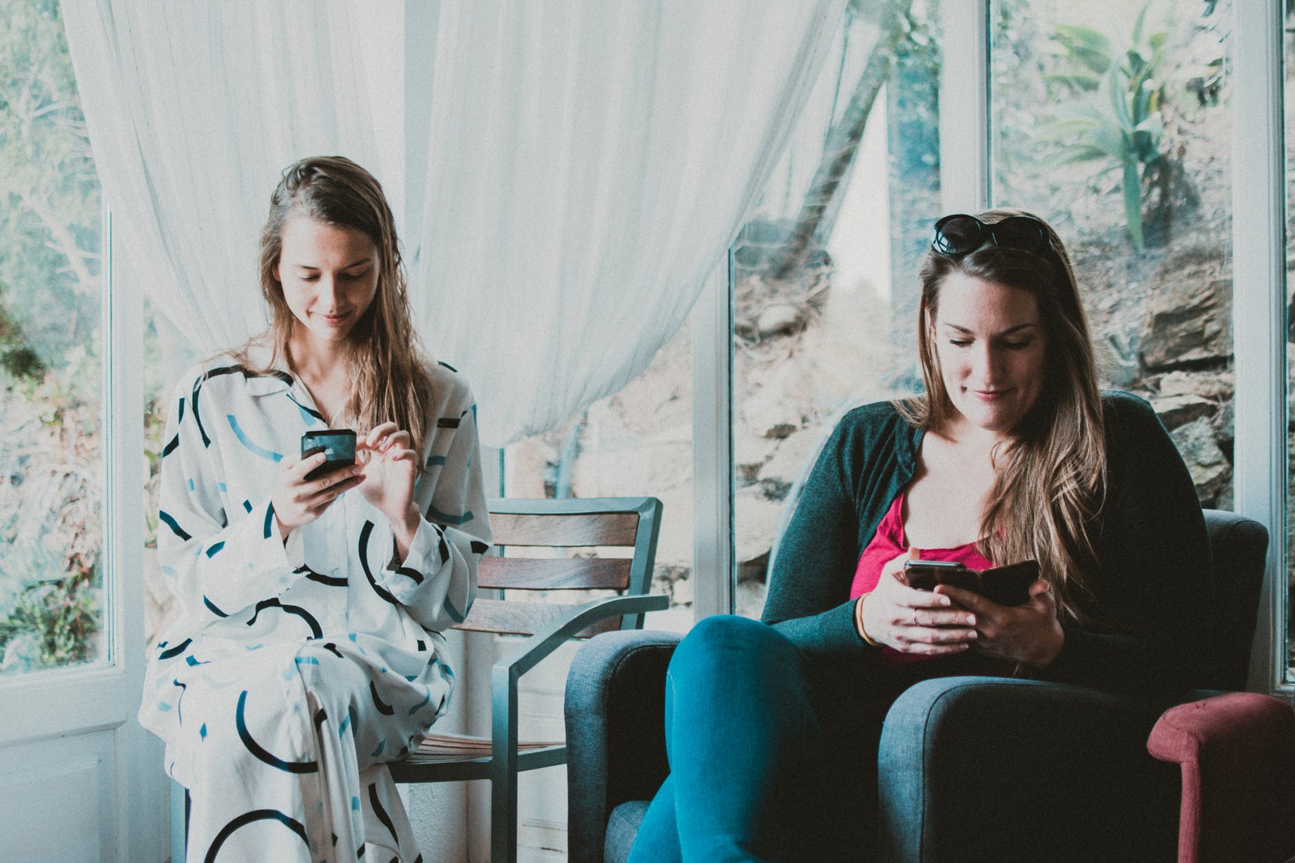 two women using smartphones inside room